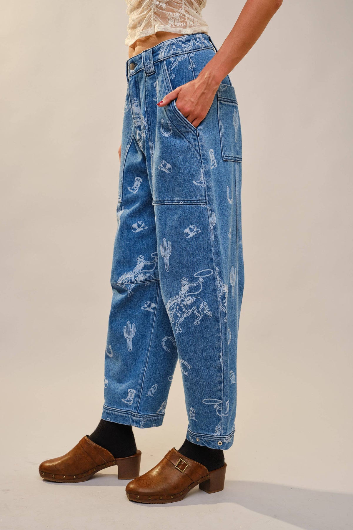 Relaxed fit barrel leg jeans with all over western rodeo print, styled with a fitted white tee