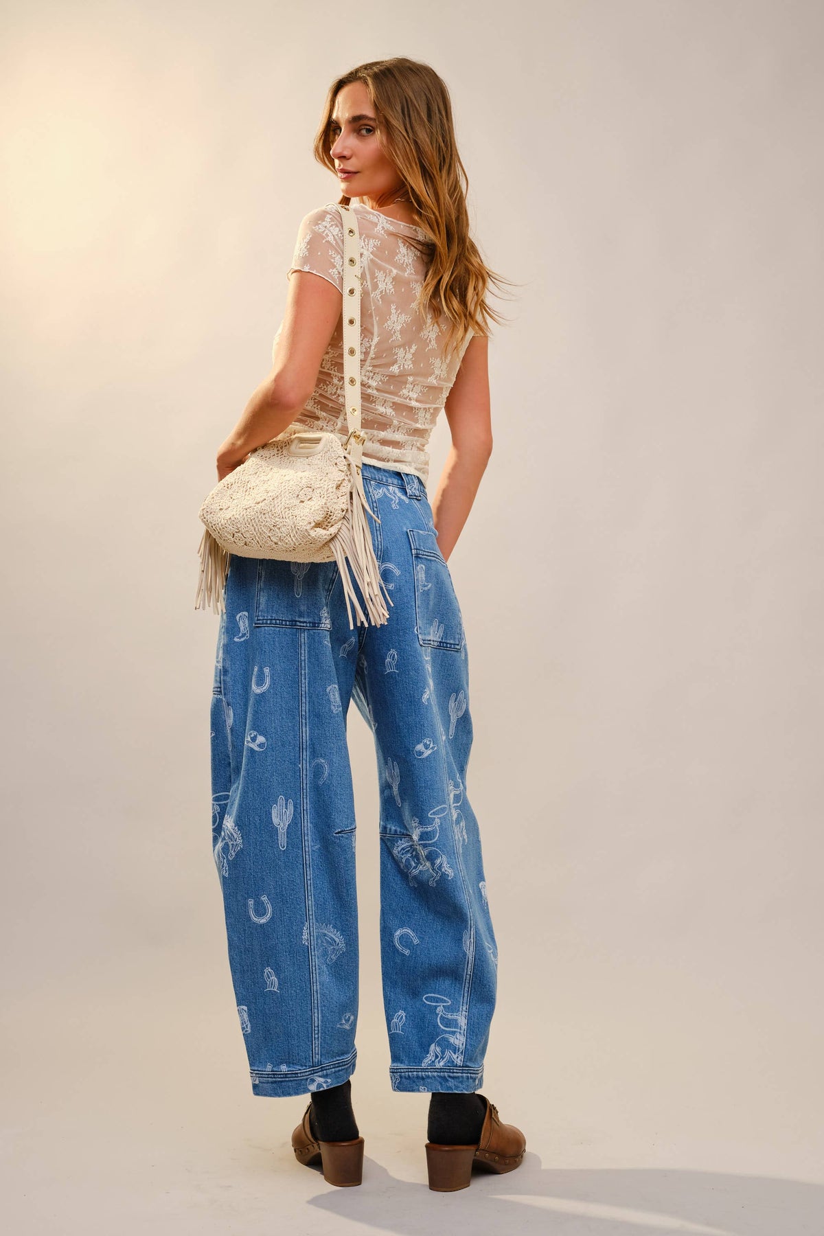 Trendy western women's jeans with relaxed barrel fit, mid blue wash and all over cowboy print