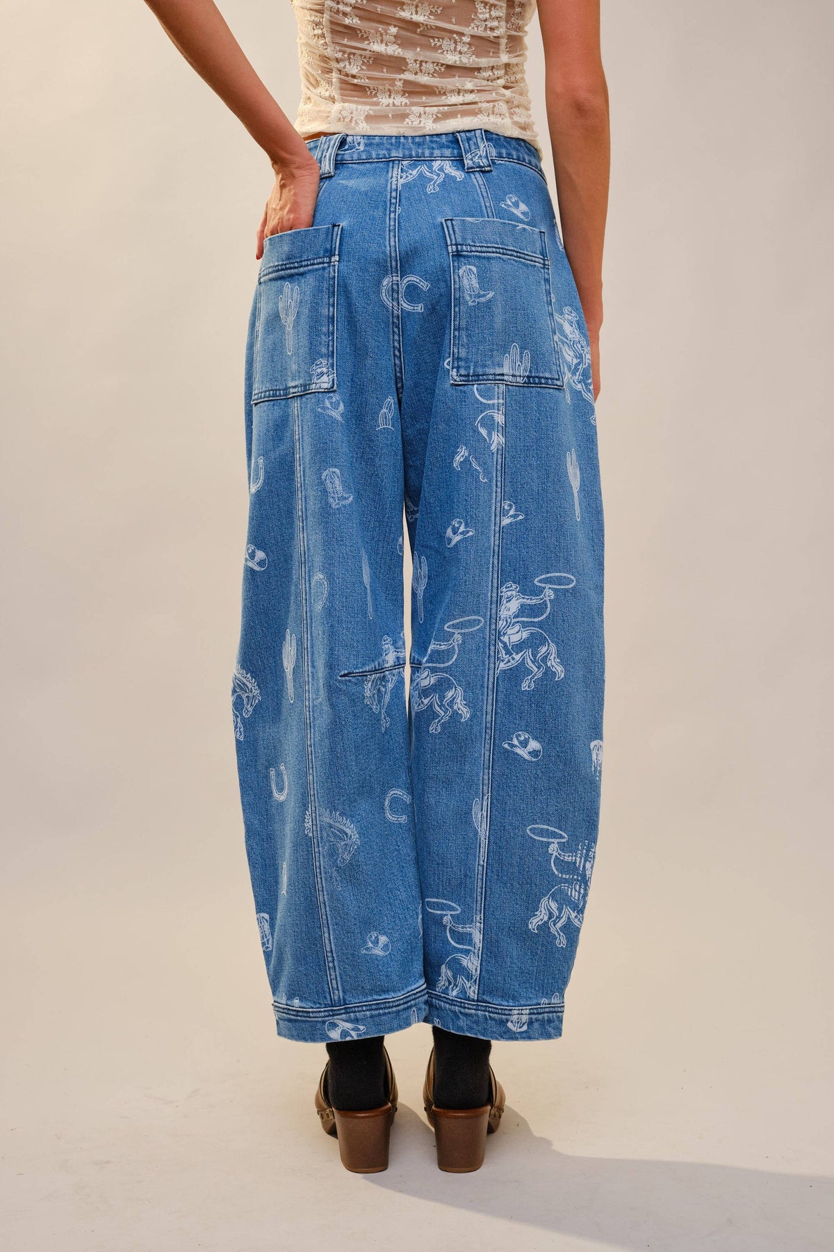 Mid wash denim barrel jeans with cowboy inspired illustrations, cactus graphics and western detailing