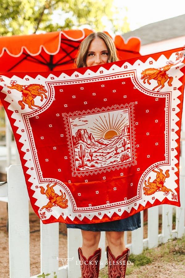 Red western wild rag featuring a desert sunrise landscape and bucking horse print