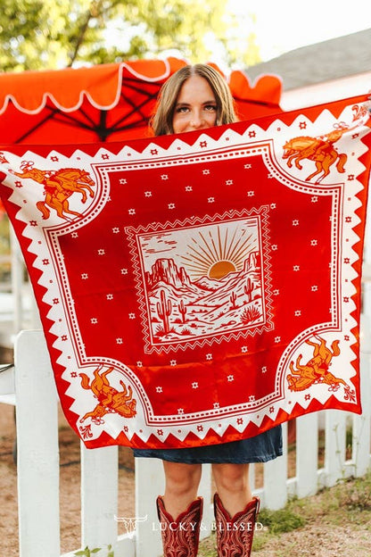 Red western wild rag featuring a desert sunrise landscape and bucking horse print