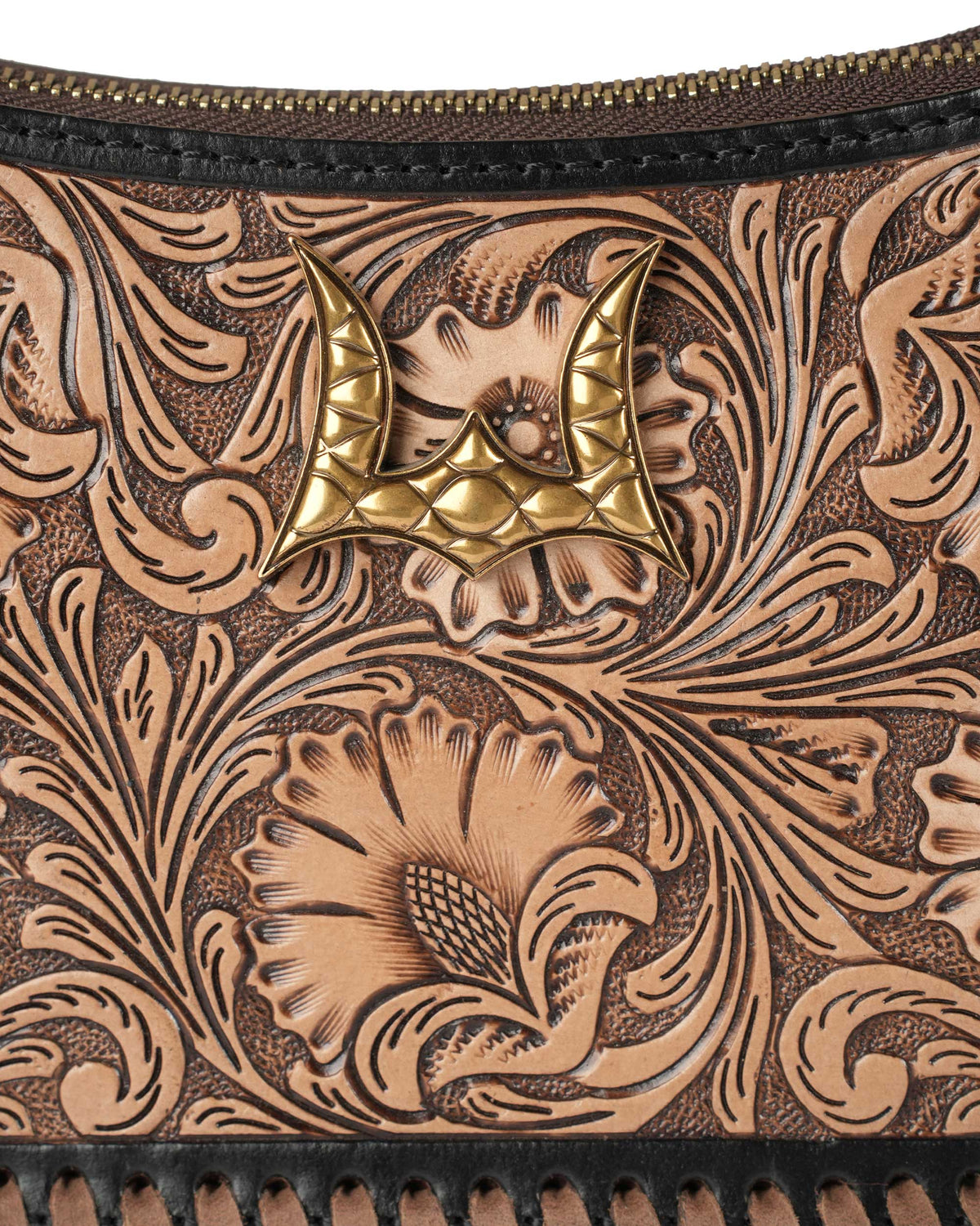 Close-up of a leather wallet with intricate tooled design and gold emblem.