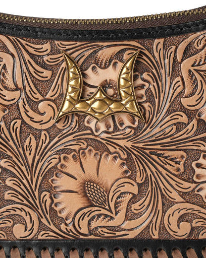 Close-up of a leather wallet with intricate tooled design and gold emblem.
