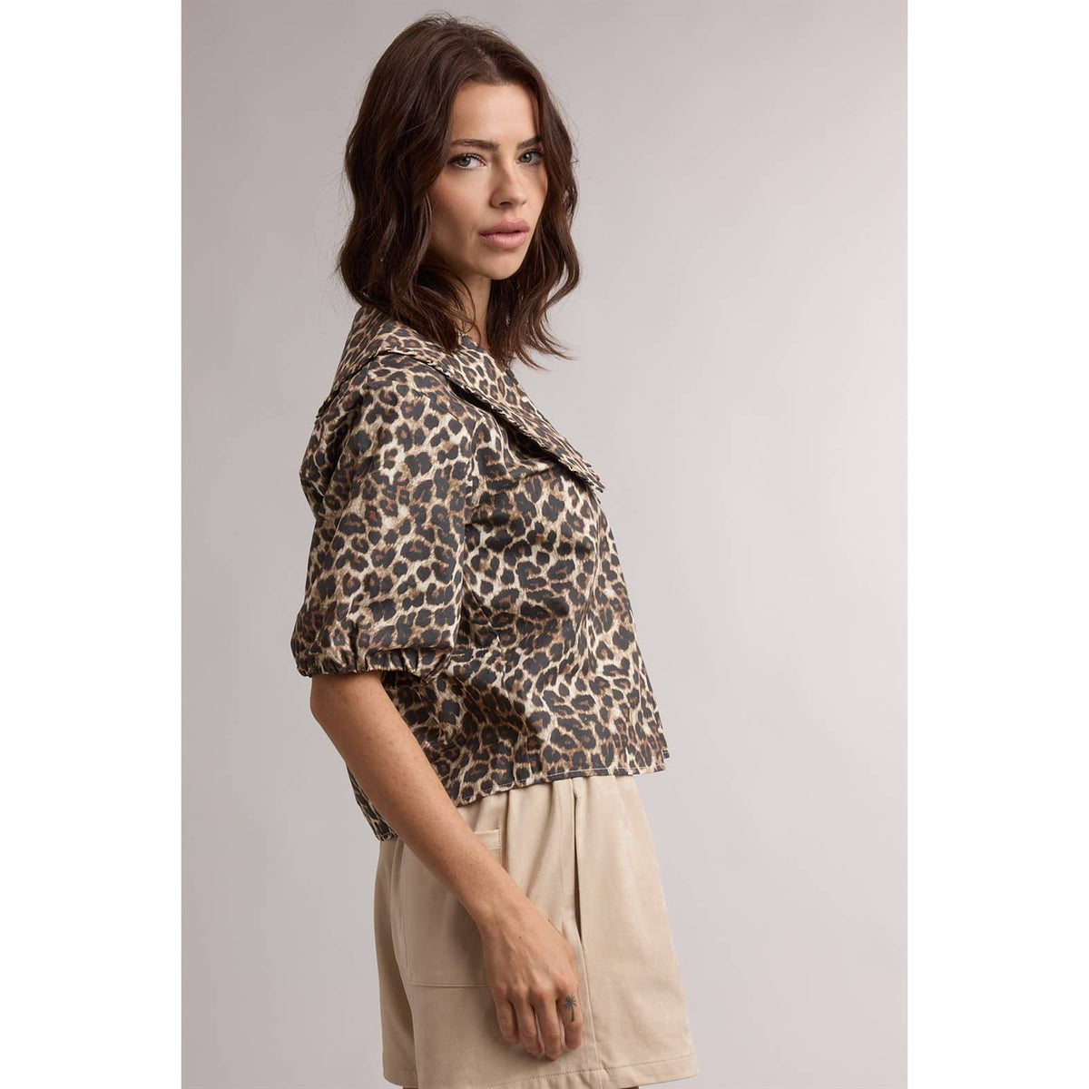 Woman wearing a leopard print jacket against a plain background