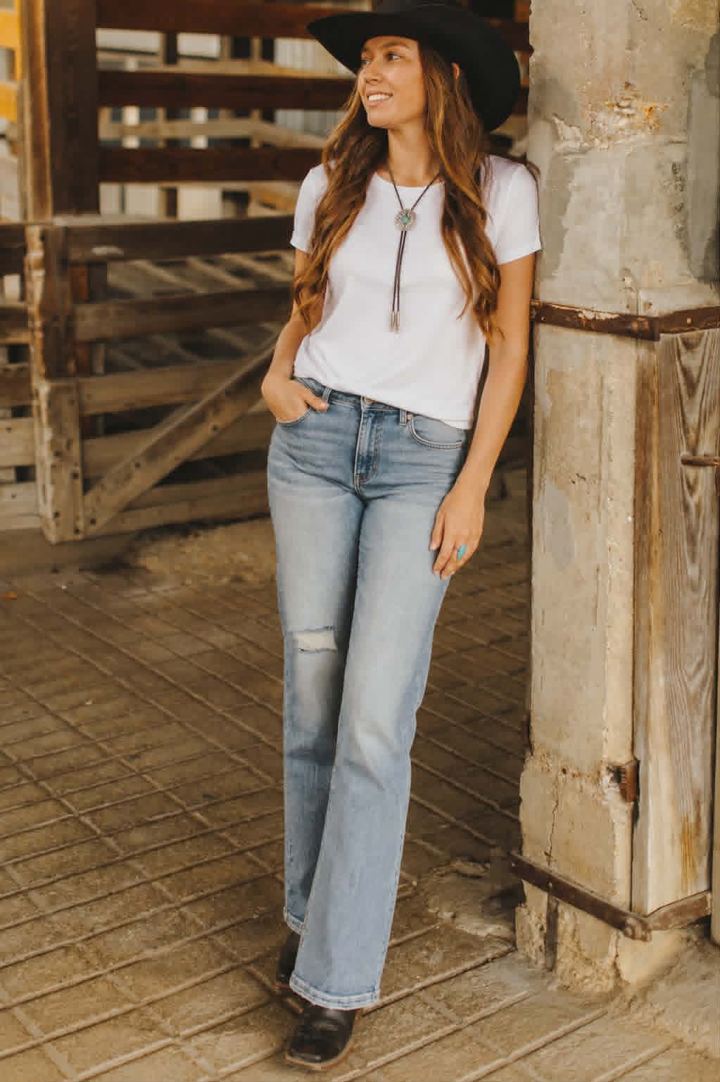 Light wash western flare jeans with distressed knee detailing and flattering high-rise fit styled with a white tee and cowboy boots.