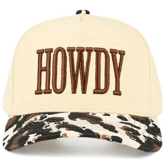front facing 5 panel trucker cap featuring cream crown panels with bold brown embroidered Howdy lettering, with cow print brim, cotton back