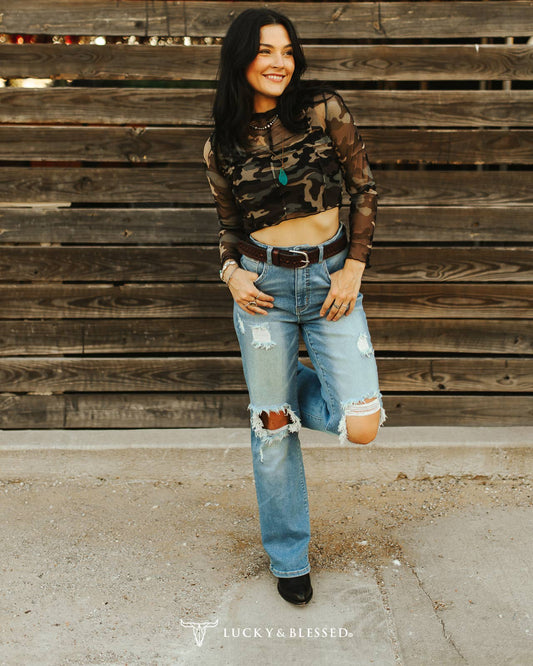 Light wash distressed western jeans featuring knee rips, a relaxed straight leg fit and high-rise waist styled with a brown woven belt