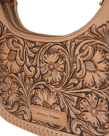 Close-up of a brown leather handbag with intricate floral embossing on a white background.