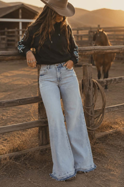 Light wash wide leg stretch denim jeans with mid rise waist and relaxed western inspired fit