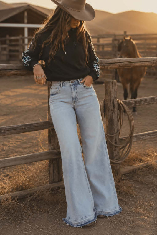 Light wash wide leg stretch denim jeans with mid rise waist and relaxed western inspired fit