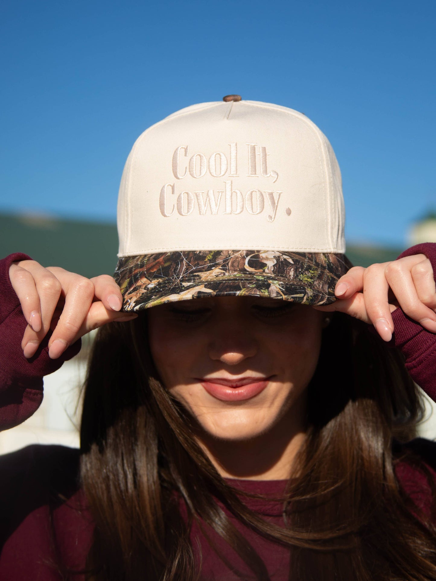 Women's western trucker cap featuring a camouflage brim and cream structured crown.