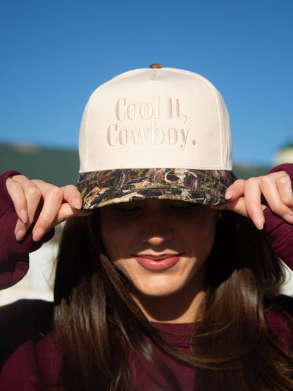 Women's western trucker cap featuring a camouflage brim and cream structured crown.