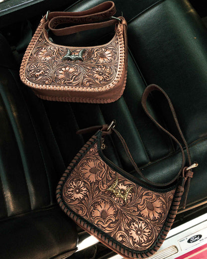 Two brown leather handbags with intricate patterns on a black leather surface.