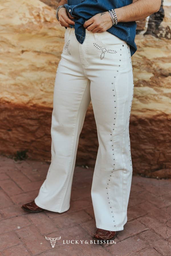 High-waisted white cowgirl jeans featuring silver stud embellishments