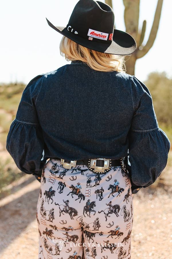 Dark denim bow neck blouse paired with printed western trousers and cowboy hat