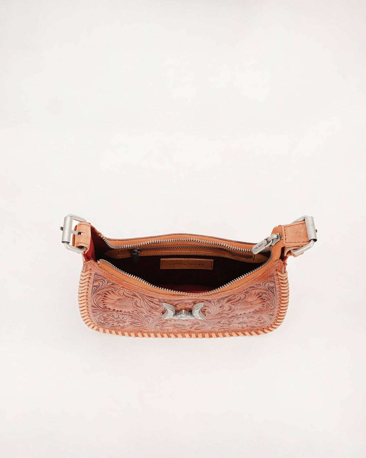 A peach-colored tooled leather shoulder bag shown open against a plain white background, displaying its interior zipper and western-style tooling details.