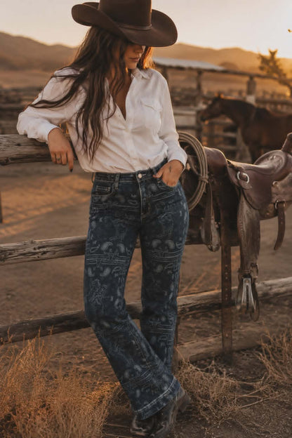 Dark wash western rodeo print jeans featuring cowboy and paisley pattern paired with cowboy boots