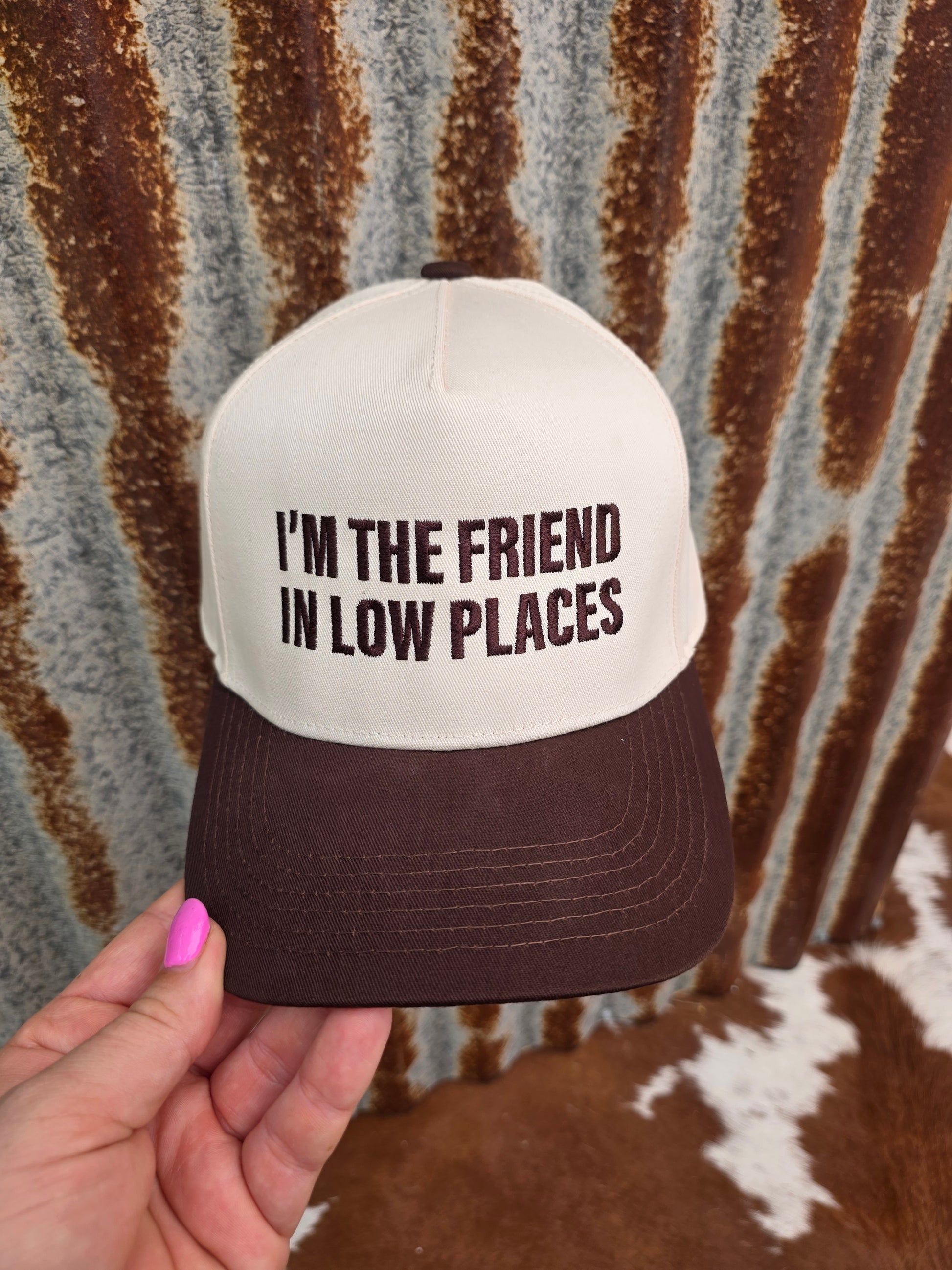 Western trucker hat with cream crown, brown curved brim and bold country music statement embroidery
