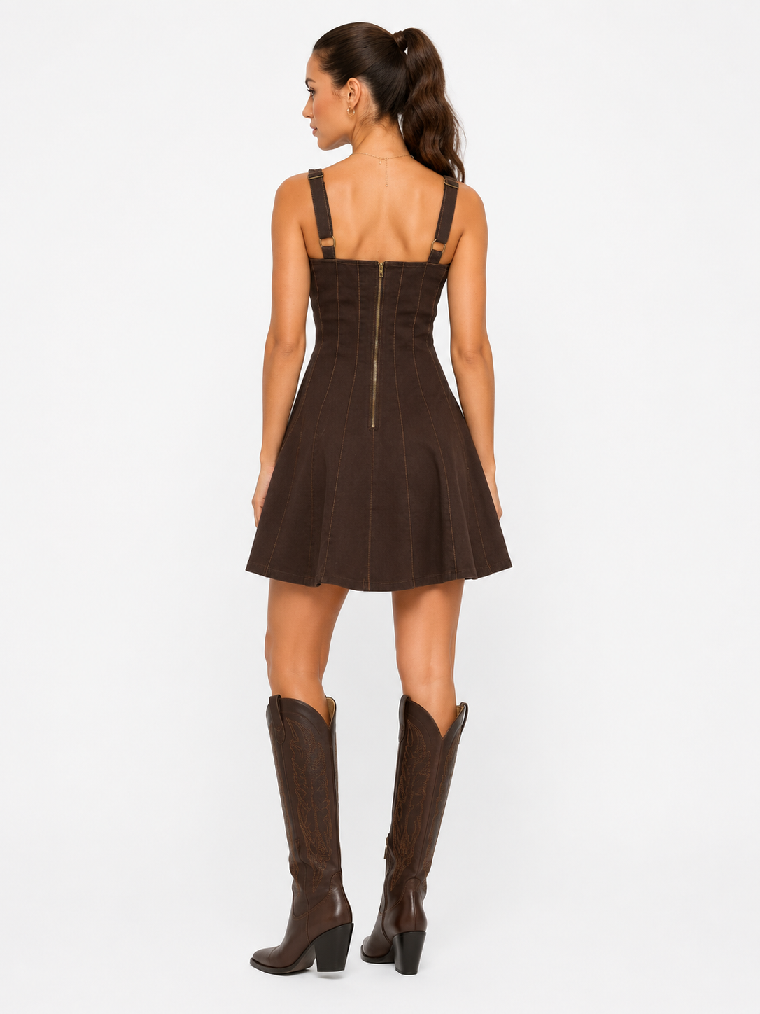 Woman wearing a brown dress with cut-out shoulders and matching knee-high boots on a white background