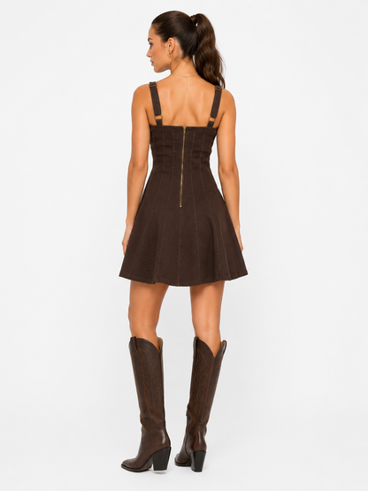 Woman wearing a brown dress with cut-out shoulders and matching knee-high boots on a white background